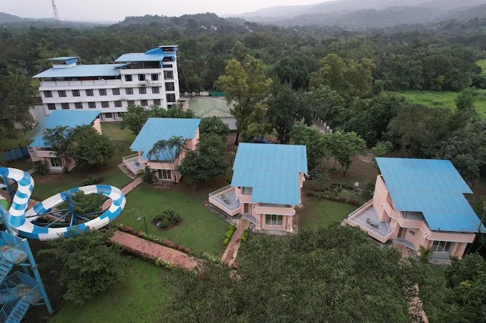Aerial view of a resort in Panvel with cottages, water park, and lush greenery during the monsoon